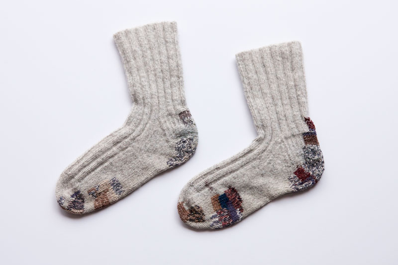Flat lay of two socks with visible mending by Amanda Rataj
