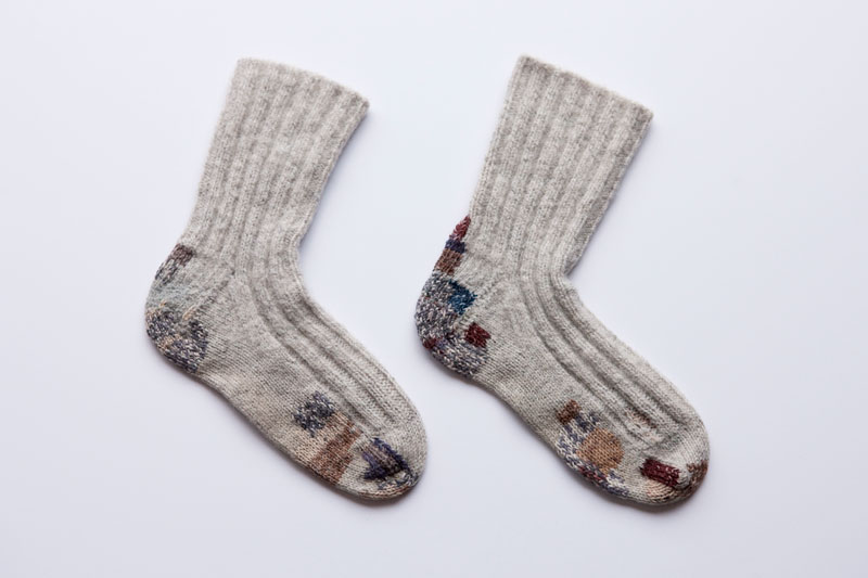 Image of two visibly mended socks by Amanda Rataj
