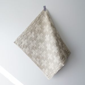 Woven napkin with cross motif hanging from corner on wall