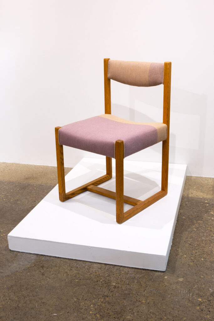 Image of a chair covered in hand woven fabric on a low plinth