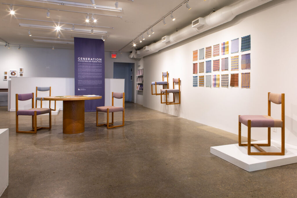 Exhibition image featuring a large room with didactic poster, chairs, and textile samples. 
